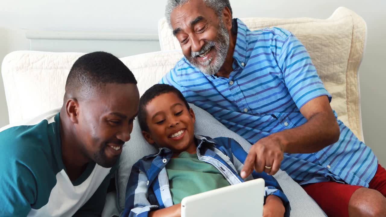 Flergenerationsfamilie bruger digital tablet i sengen