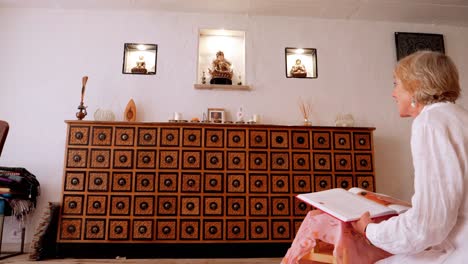 Blonde-Woman-Reading-a-Book,-Glancing-up-at-Buddha-Statue-in-Slow-Motion