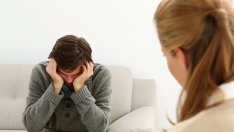 young man sitting on sofa talking to his therapist