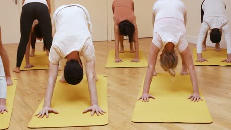 Trainer-assisting-group-of-people-with-stretching-exercise-