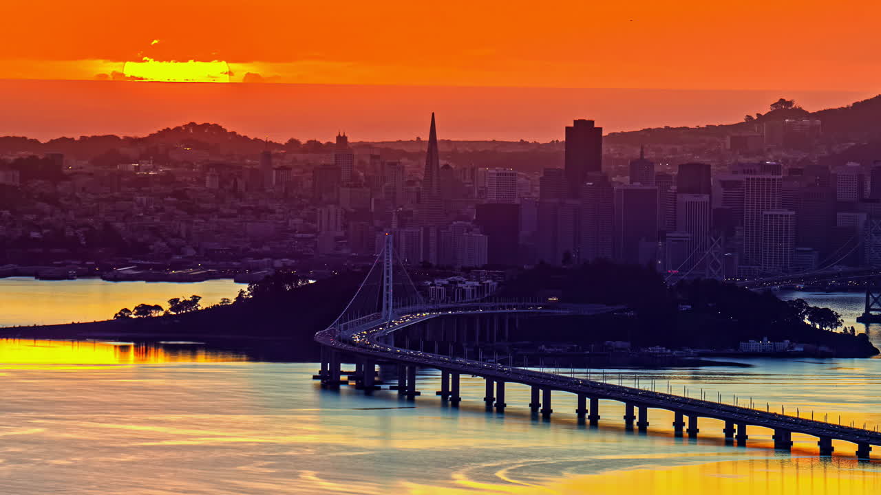 Time-lapse sunset over San Francisco skyline and Oakland Bay Bridge in golden light