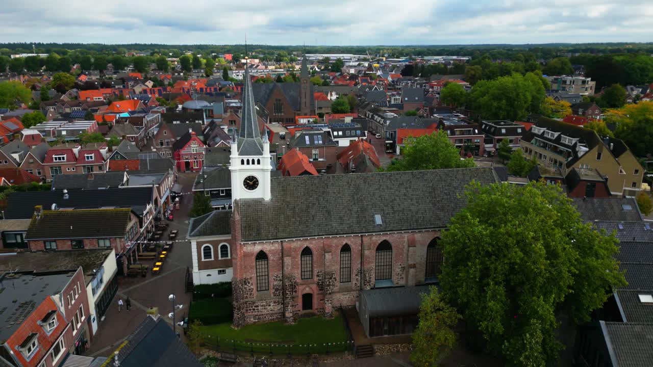 Elevated drone footage showing Ommen’s main church with white spire, gothic windows, and clock tower. Captured in Ommen, Overijssel, Netherlands (Ommen, Overijssel, Nederland)
