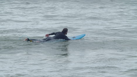 Sportlicher-Mann-Im-Neoprenanzug-Mit-Künstlichem-Bein,-Der-Auf-Surfbrett-Liegt-Und-Im-Ozean-Schwimmt-3