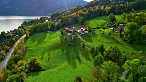 Eine-Rustikale-Grüne-Landschaft-Eines-Dorfes-Auf-Einem-Hügel-In-Der-Nähe-Eines-Sees-Mit-Bunten-Bäumen
