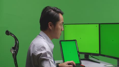 persona que trabaja en una computadora con monitores de pantalla verde