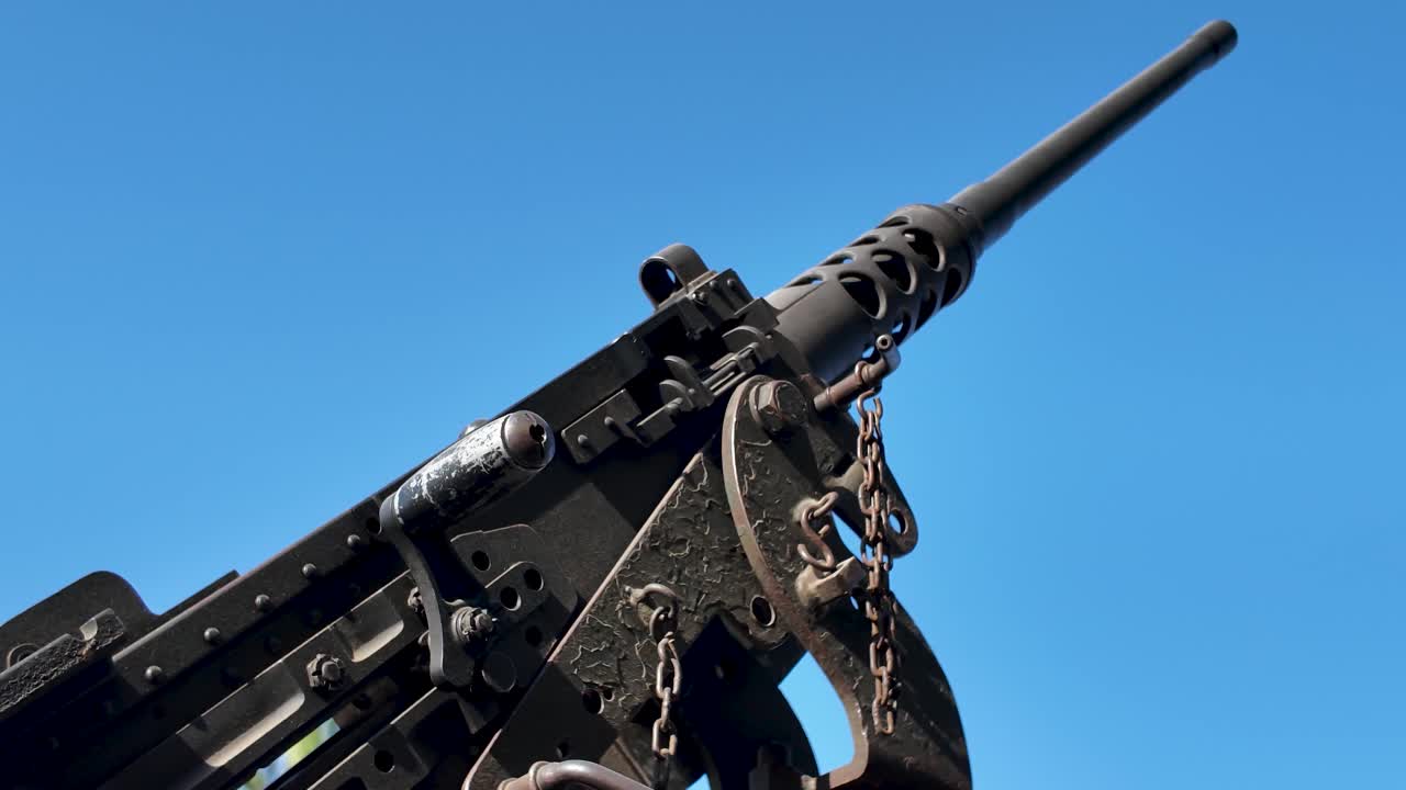 Close up of a Browning M2 heavy machine gun mounted on a vehicle, ready for action under a clear blue sky