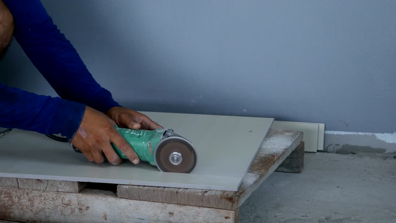 lavoratore che taglia una piastrella utilizzando una smerigliatrice angolare in cantiere