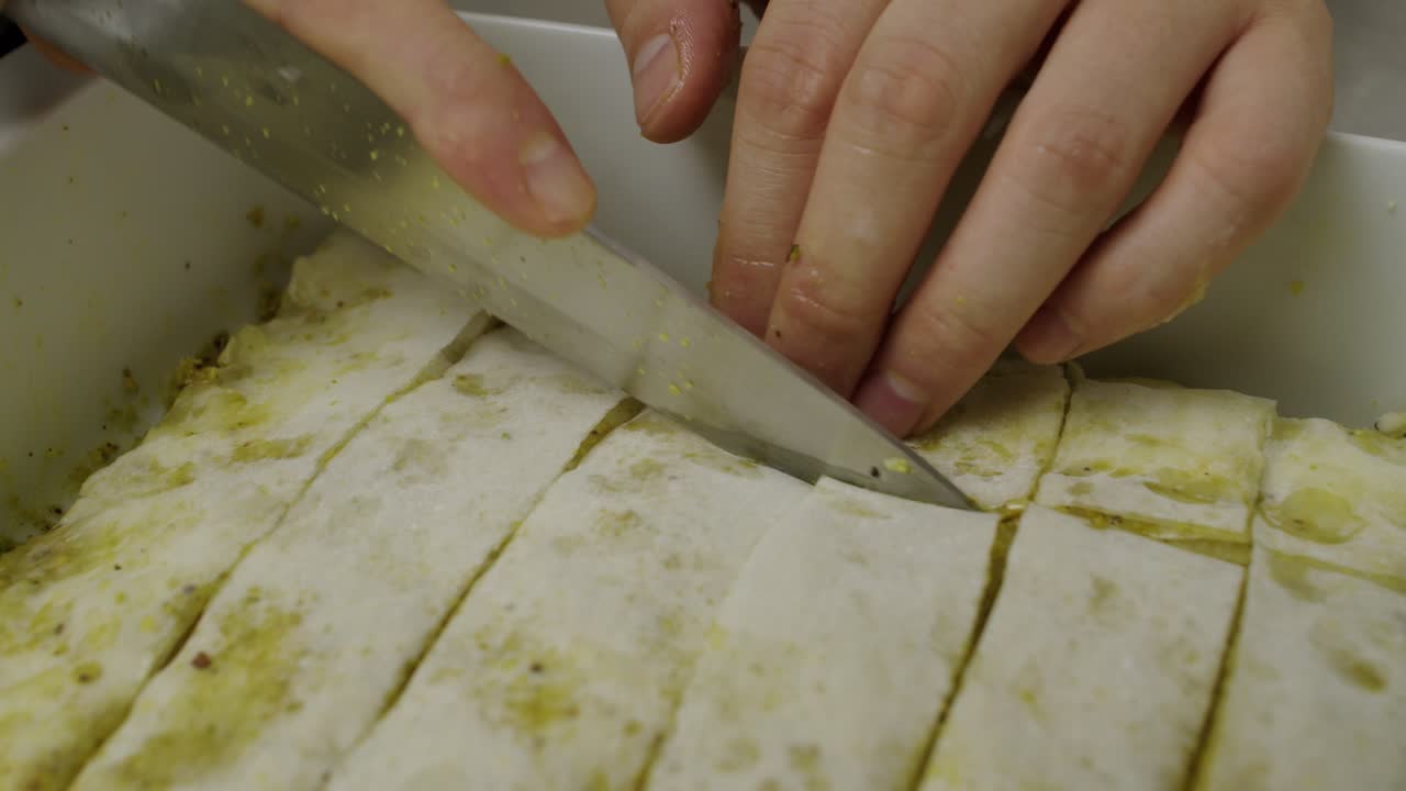 cortando el postre baklava en rodajas dentro de la bandeja de cocción de cerámica