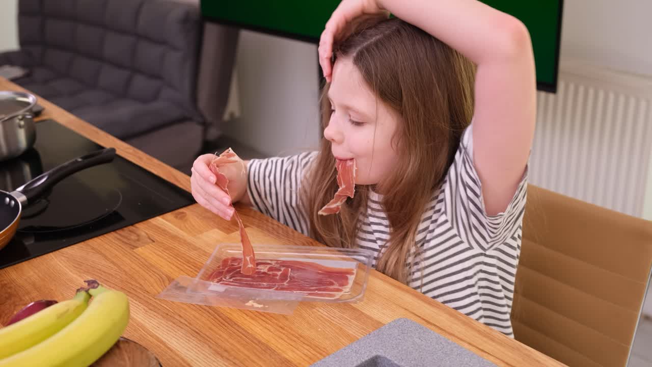 Girl eating prosciutto in the kitchen