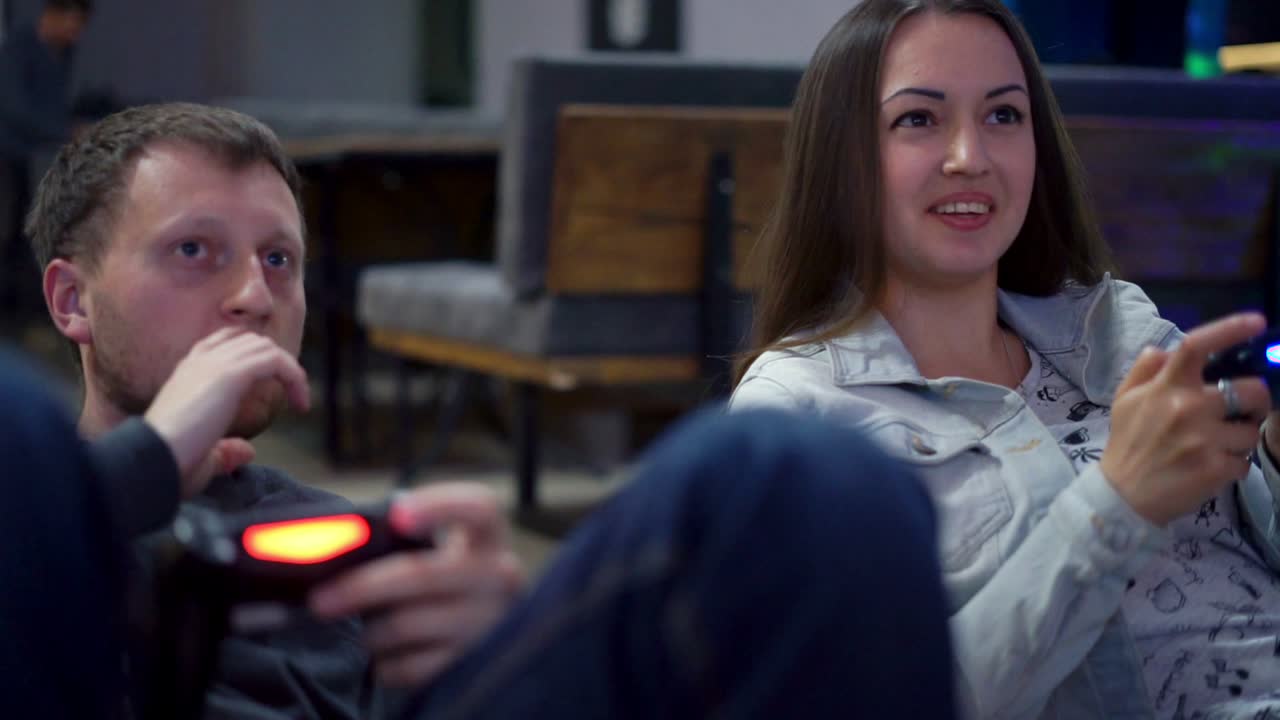 una pareja joven jugando un videojuego en casa. un hombre explicando cómo jugar y usar el controlador de juego. controlador de juego inalámbrico