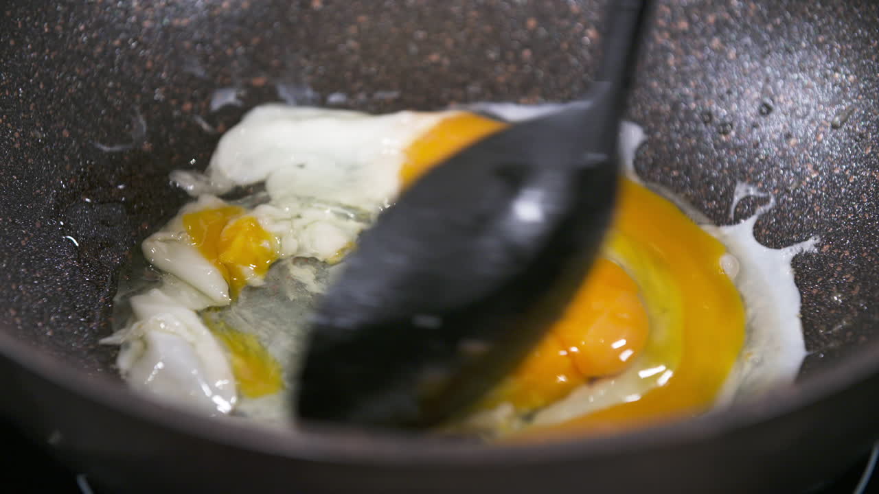 huevos revueltos en una sartén negra, huevos revueltos, mezcla de clara de huevo y yema de huevo en una sartén