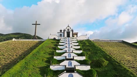 Drone-zooms-Old-european-white-chapel-architecture,-green-meadow-Azores-Portugal