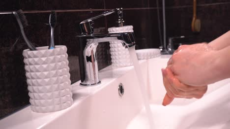 The-girl-takes-the-soap-and-washes-her-hands-in-the-bathroom