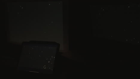 tight shot of three digital computer devices flashing a strobing static noise signal in a dark room