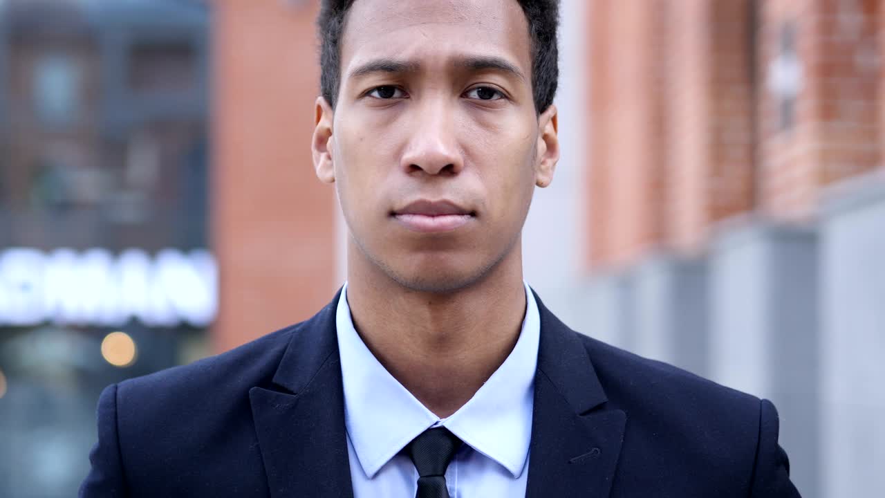 심각한 아프리카 사업가 벤치에 앉아 주변을 둘러보고