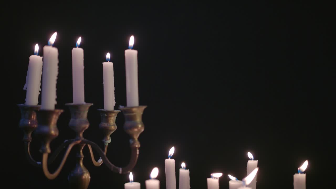 un grupo de velas blancas, algunas en un candelabro, encendidas y funcionando durante un tiempo