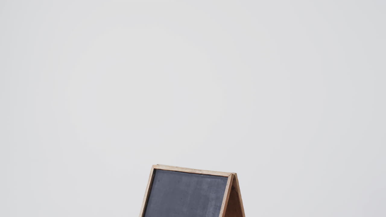Video of blackboard sign on wooden stand with copy space on white background