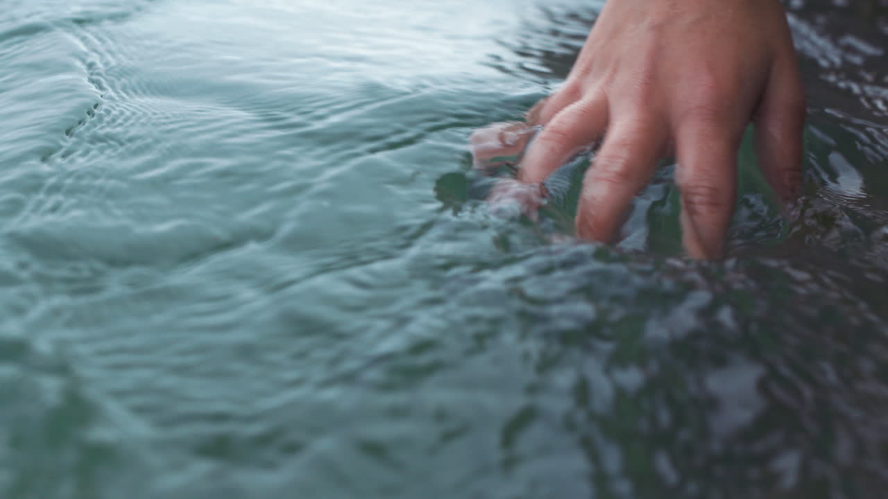 Manicure hand of woman touch water in sea