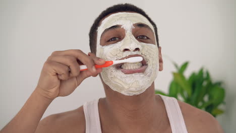 handsome black man with facial mask brushes his teeth 2