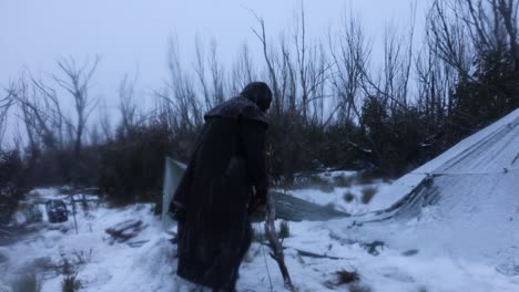 a bushman caught in a snow storm tries to set up survival shelter tarps in the mountains