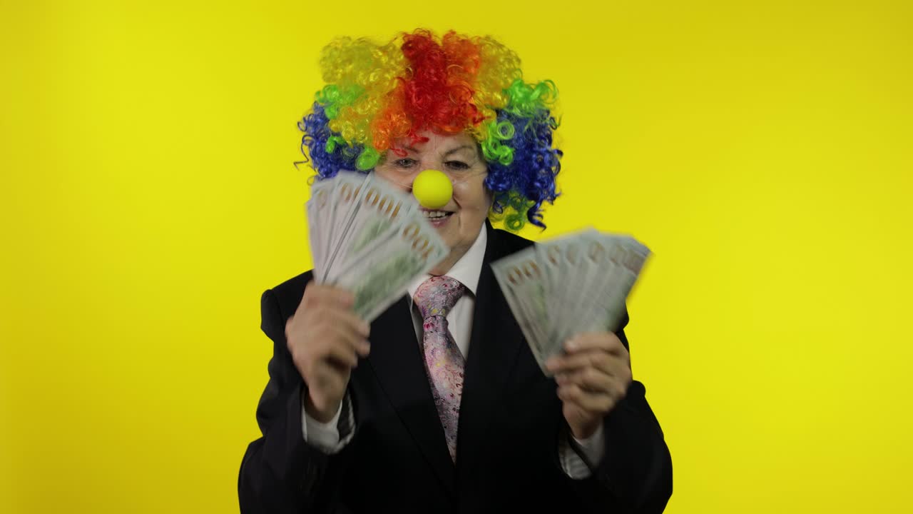 Anziana imprenditrice clown, libera professionista e capo, che balla con banconote in contanti.