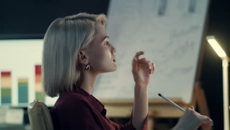 mujer de negocios reflexiva analizando gráficos en la computadora en la oficina nocturna