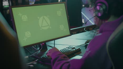 side view of an male gamer playing virtual video games on professional powerful computer with green screen display