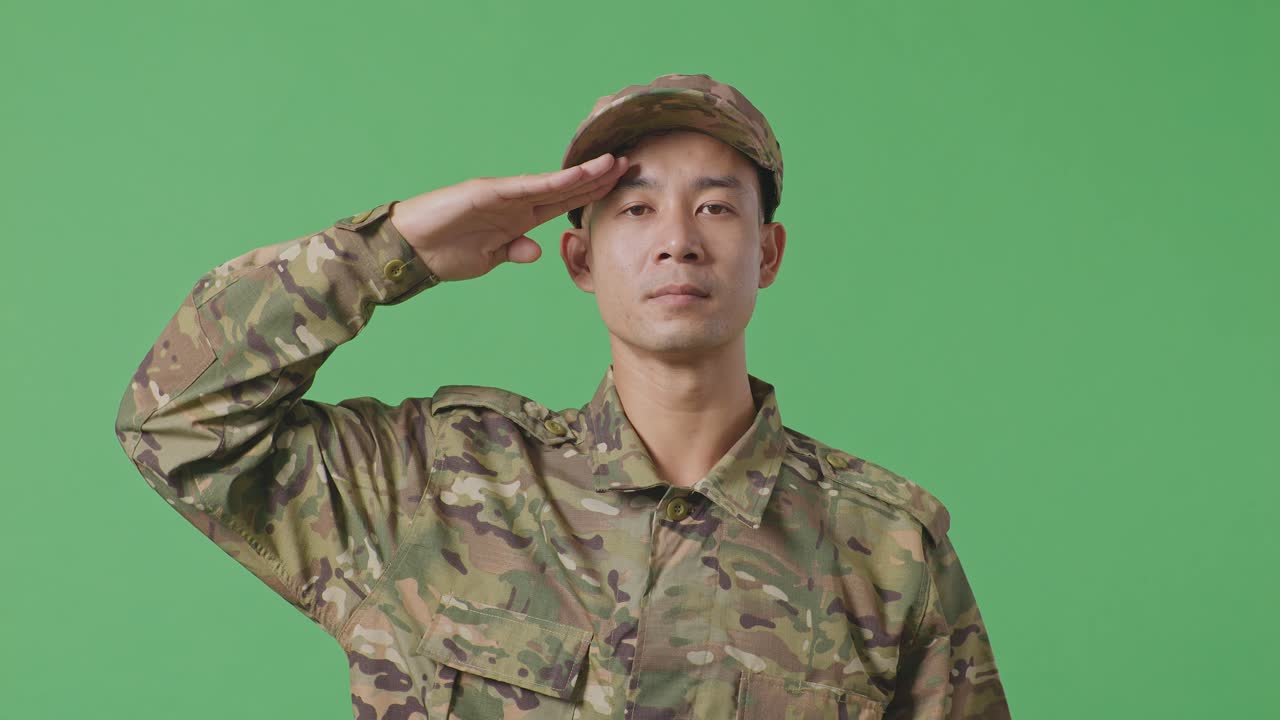 Close Up Of Asian Man Soldier Saluting While Standing In The Green Screen Background Studio
