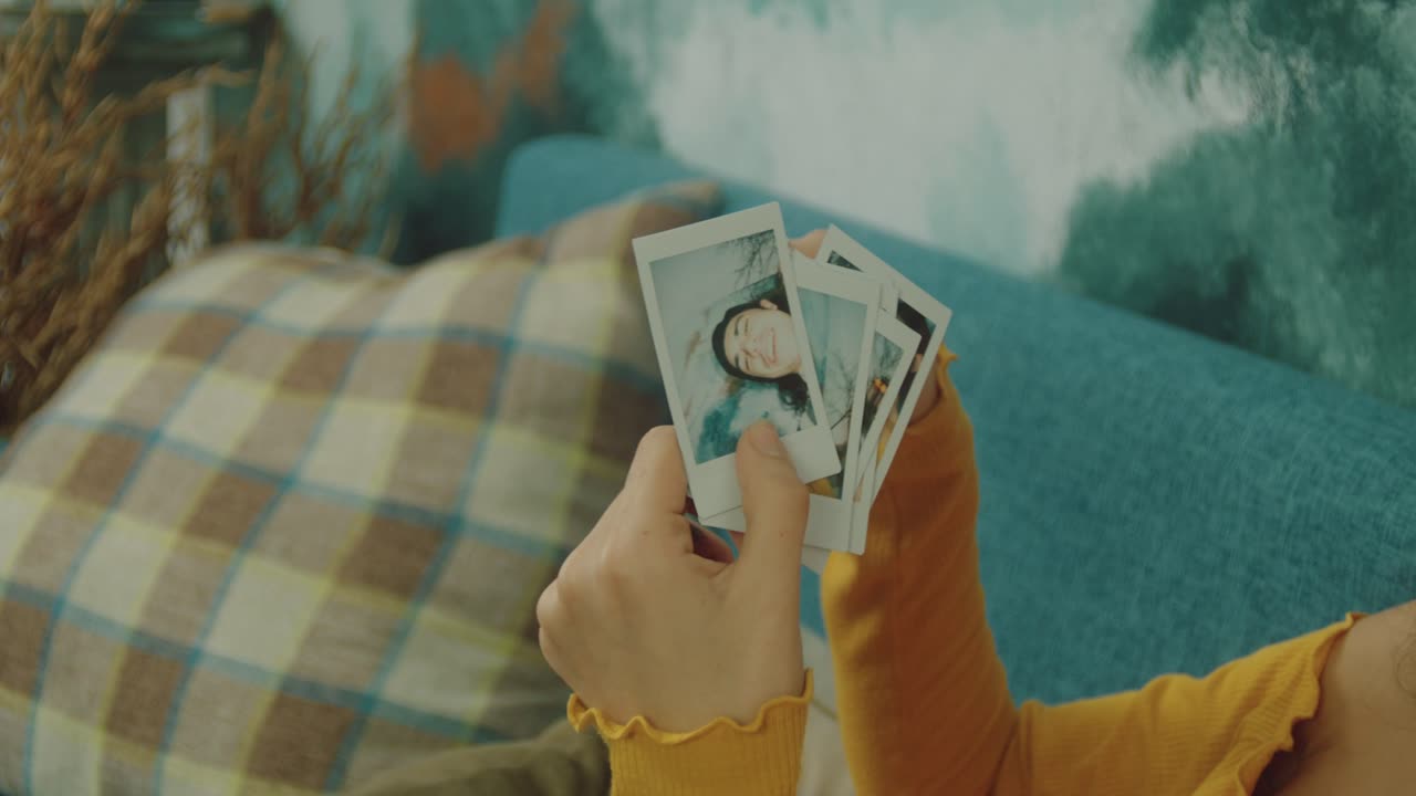 Woman looking at instant photos on a couch