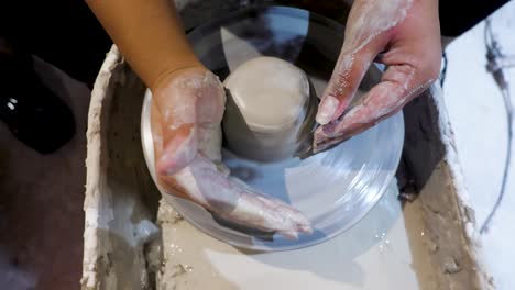 side view of an african american hands spinning clay very sporadically while the wet molded clay moves violently through the fingers