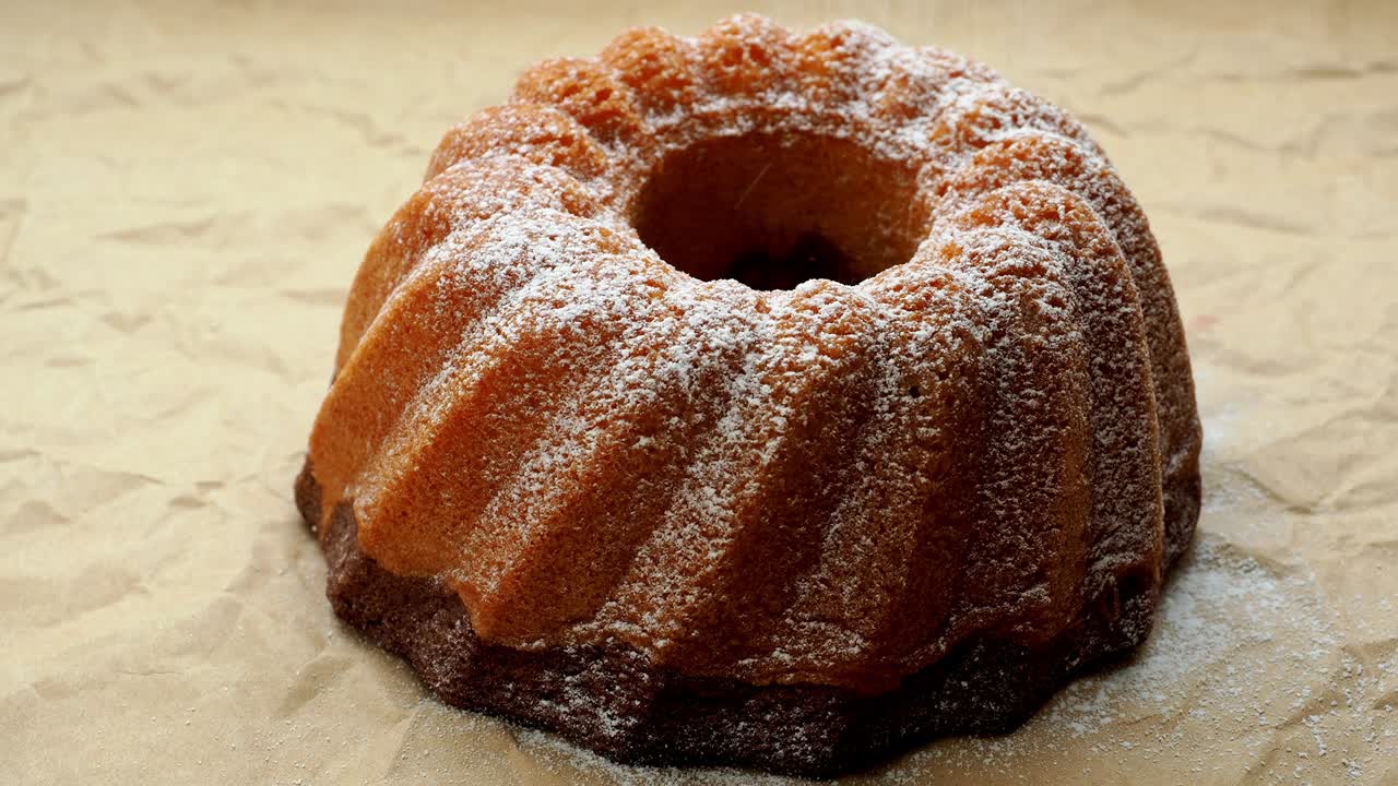 pastel de mármol entero recién horneado hecho en casa cubierto con azúcar en polvo en papel. resolución 4k.