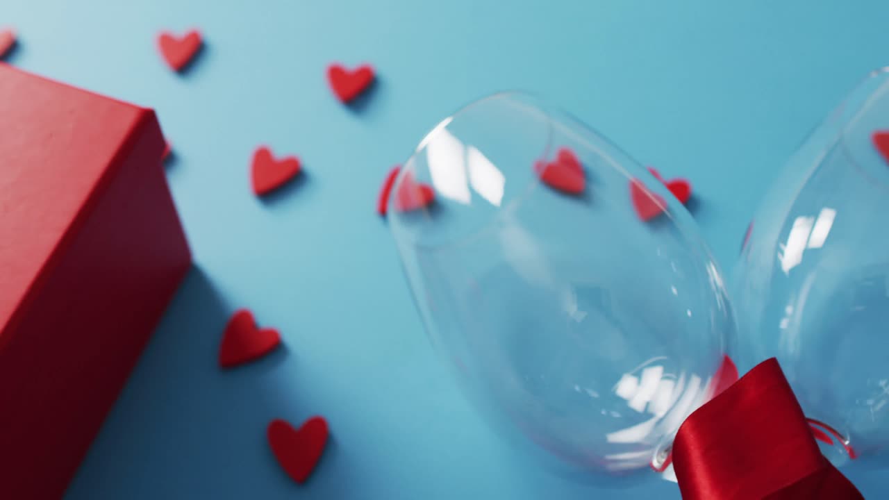 Present, hearts and wine glasses on blue background at valentine's day
