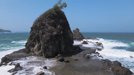 vista aérea de una isla de coral en el mar golpeada por olas de marea con cielo azul en el fondo