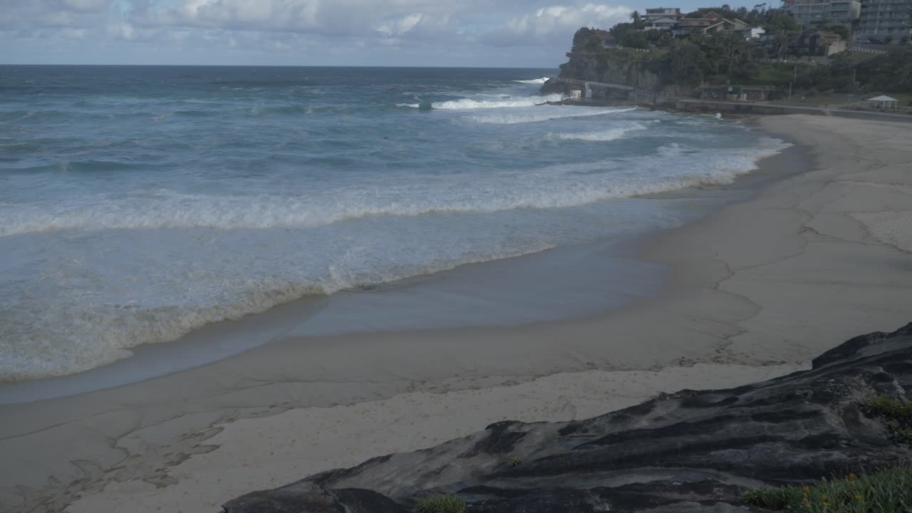 olas oceánicas que se lavan en la orilla arenosa de la playa de bronte - paseo costero - coronavirus - sydney, nsw, australia