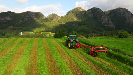Low-aerial-behind-mower-conditioner-behind-tractor-cutting-down-lush-green-crop