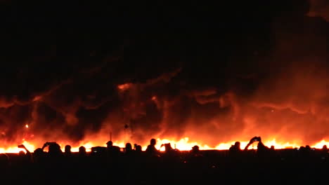 un muro pirotécnico de fuego explota frente al público al final de un espectáculo aéreo.