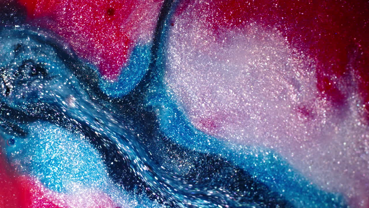 Vibrant red, blue, and white substances blending in a sparkling close-up macro shot