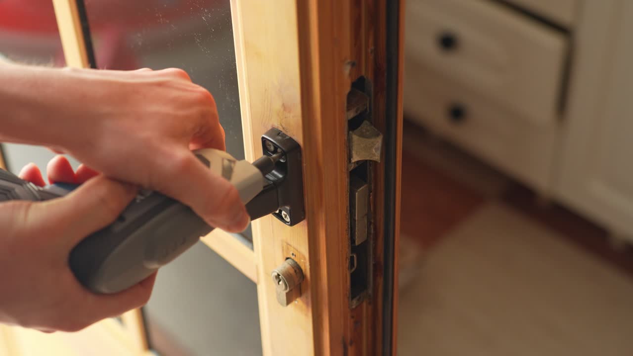 High angle closeup of hands unscrewing broken door lock, door repair