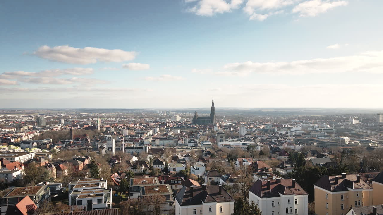 Drone aereo 4K che si alza dal livello stradale di Ulm verso un vasto paesaggio urbano. Filmato Premium che rivela la guglia della cattedrale, edifici residenziali e viste panoramiche della città. Ideale per video di viaggi e aziendali.