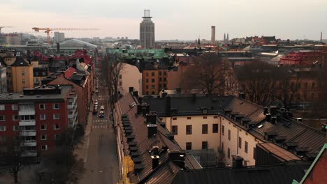 Low-drone-flight-above-residential-block-of-houses-in-urban-neighbourhood.-Arm-of-construction-crane-in-distance.--Stockholm,-Sweden