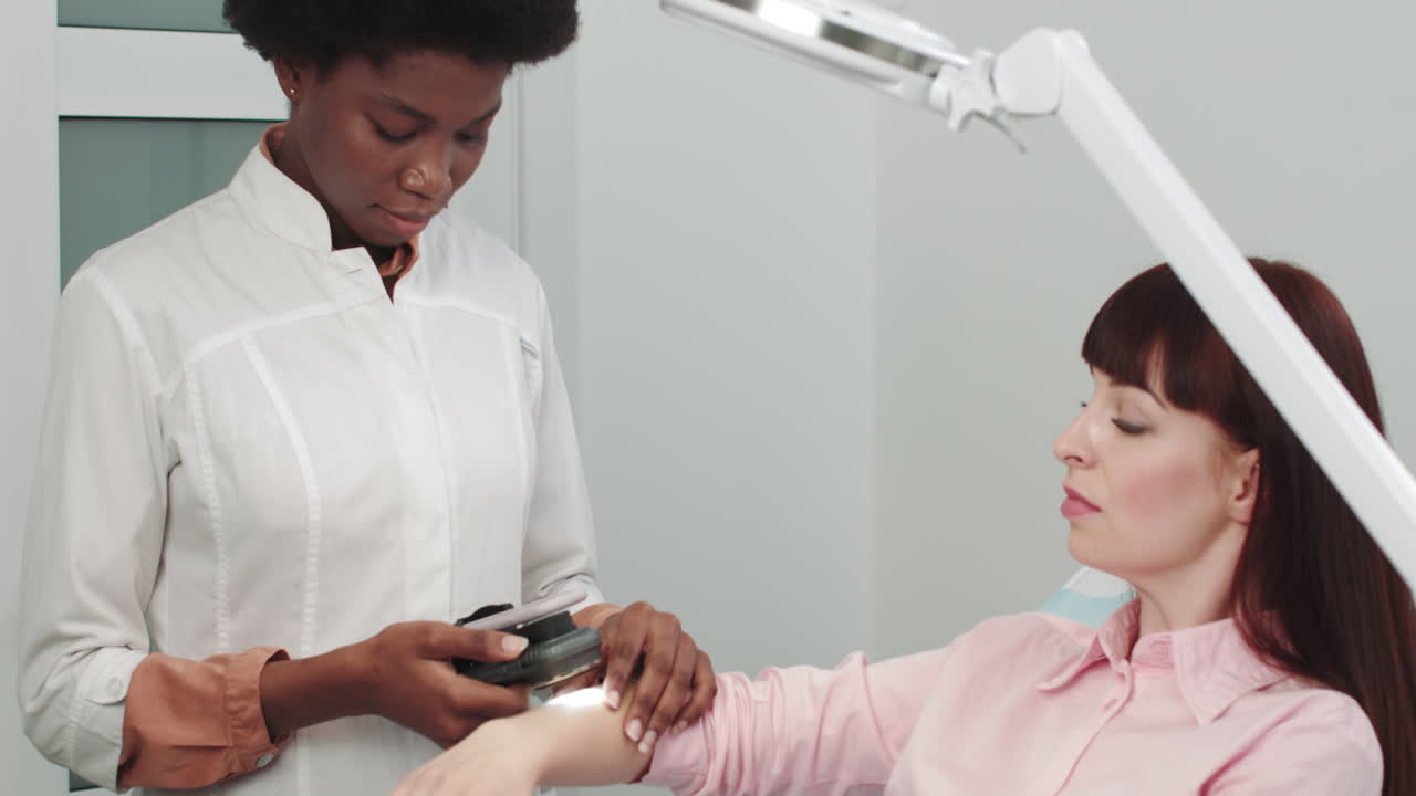 Un dermatólogo examina la piel de un médico profesional. El dermatólogo investiga una marca de nacimiento en la piel.