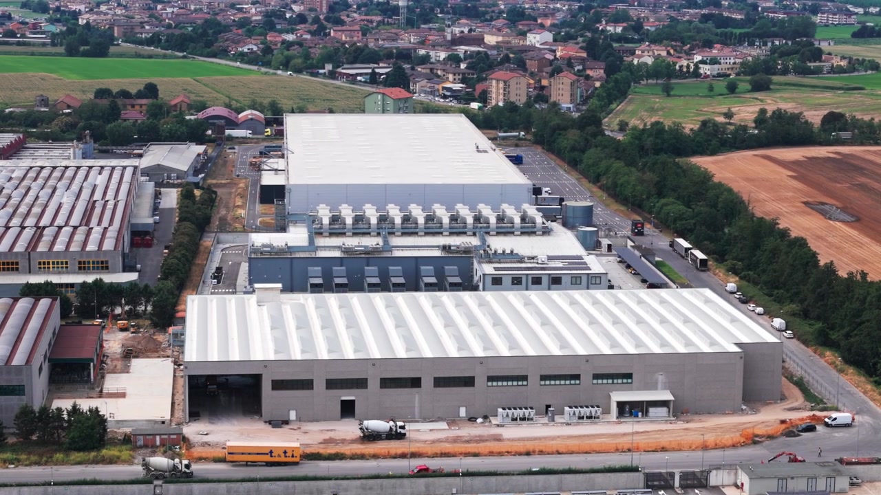Paesaggio industriale che mostra una vista aerea di un grande e moderno complesso di datacenter. La struttura presenta sistemi di raffreddamento avanzati sul tetto