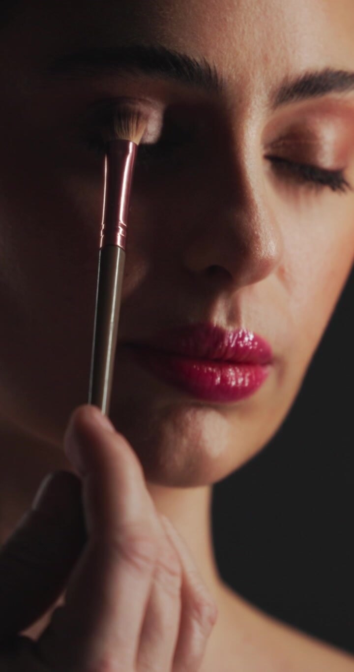Makeupartist påfører øjenskygge på kvindes øjenlåg