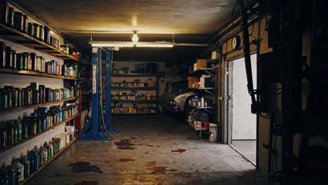 wide-angle shot of a dimly lit garage with shelves of supplies and a vintage car
