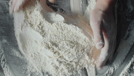 man piling flour into mound with well in center