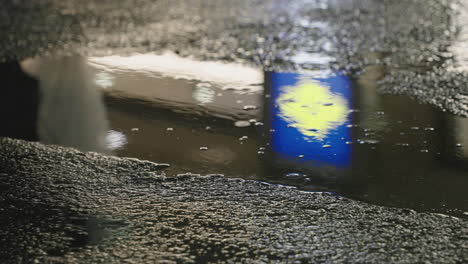 Reflection-In-A-Puddle-Of-A-Person-Walking-On-The-Road-During-Night-In-Tokyo,-Japan