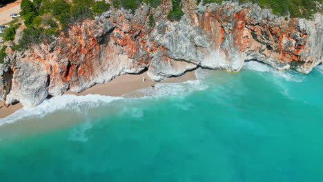 drone aéreo en movimiento hacia adelante disparado sobre acantilados rocosos empinados a lo largo de la playa de gjipe, albania en un día soleado