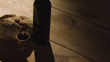concepto religioso filmado con pan de cáliz y vino en una mesa de madera con piscina de luz 2