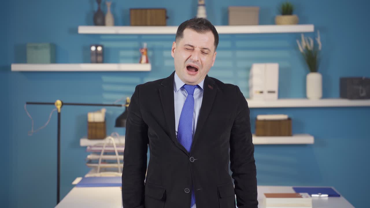 피곤한 사업가가 졸린 눈으로 카메라를 쳐다보고 있습니다.