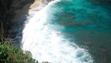 top view of crashing wave spreads white wash over broken beach, nusa penida, bali